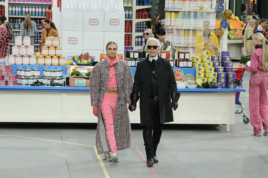 Chief of Chanel Karl Lagerfeld, with supermodel Cara Delevingne, walking down his supermarket runway.