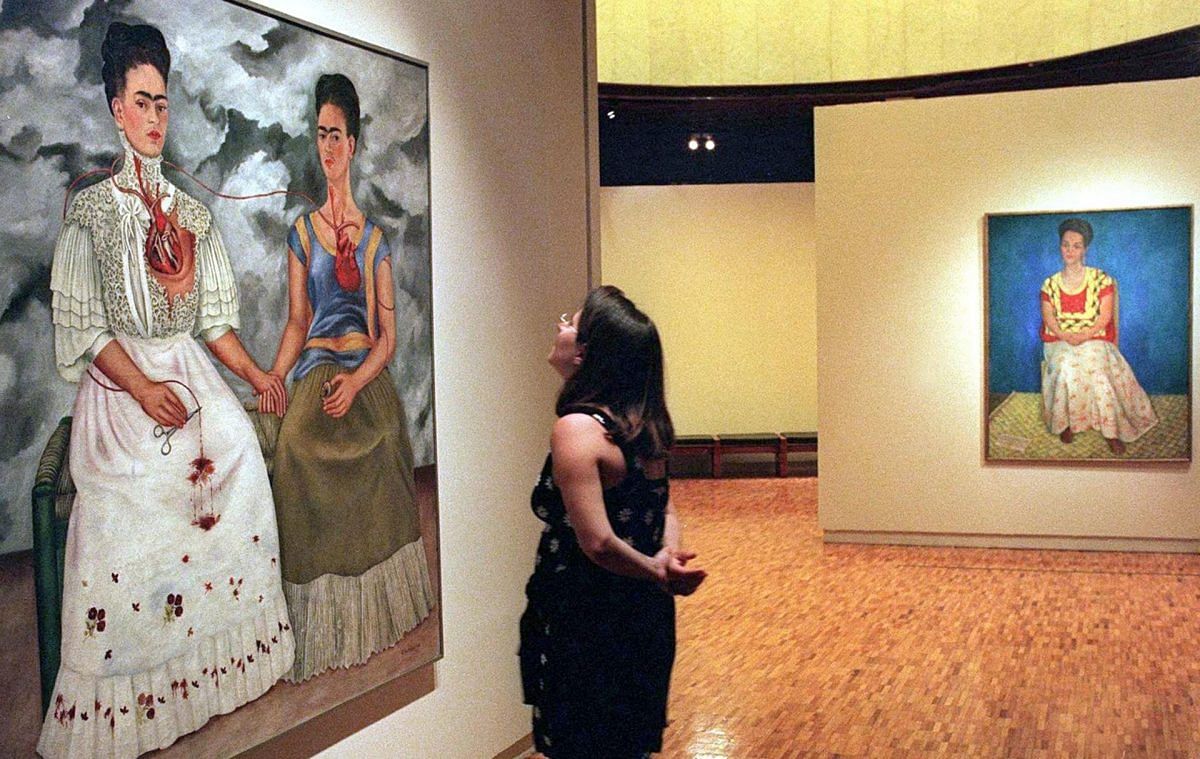 A visitor at the Modern Art Museum of Mexico City looks at a double auto-portrait by Mexican artist Frida Kahlo 22 August 1999. AFP PHOTO/Ramon CAVALLO (Photo by RAMON CAVALLO / AFP)