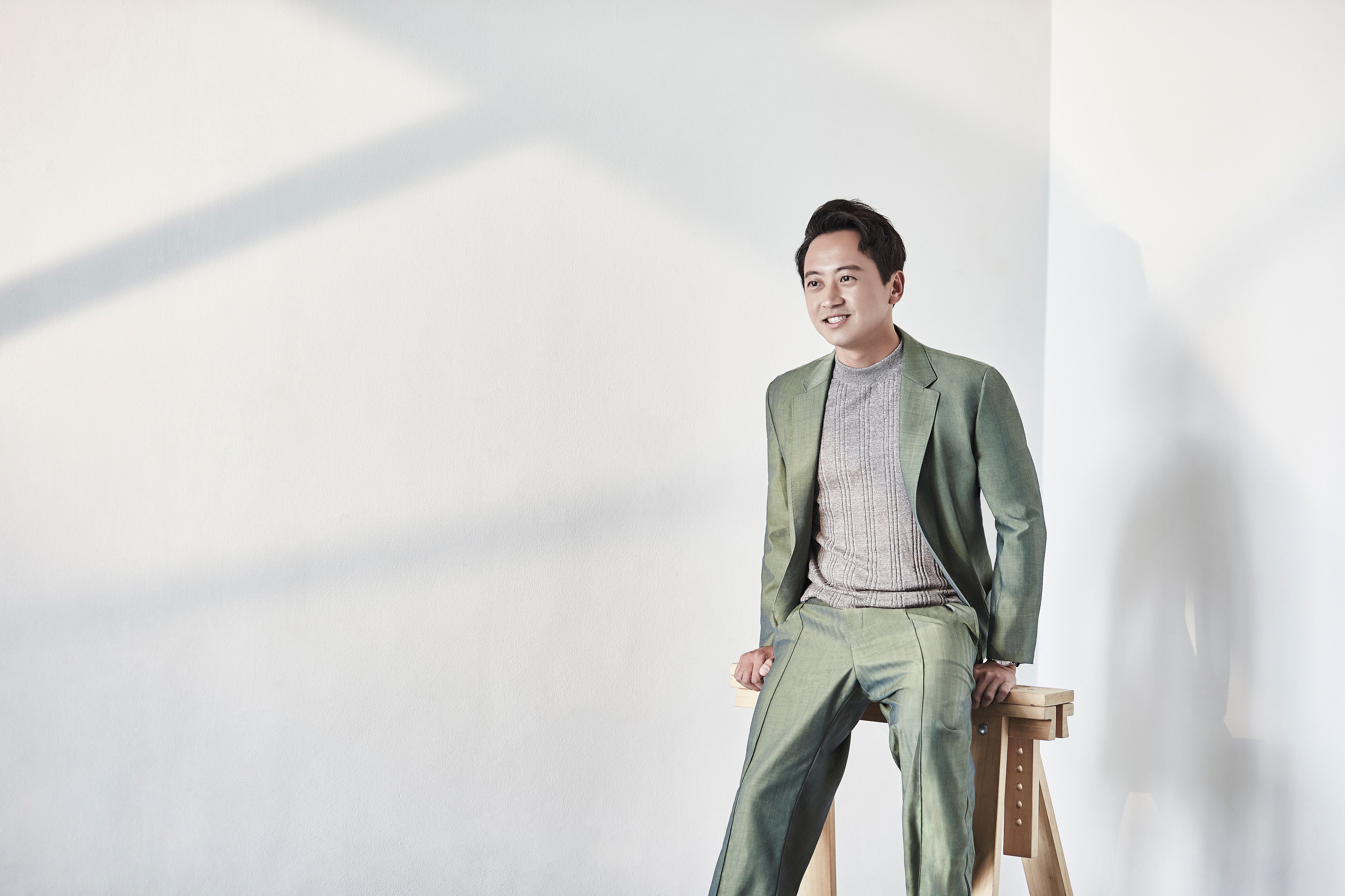 Andy Lim is wearing an olive green jacket with trousers and a crew neck sweater from Z Zegna.