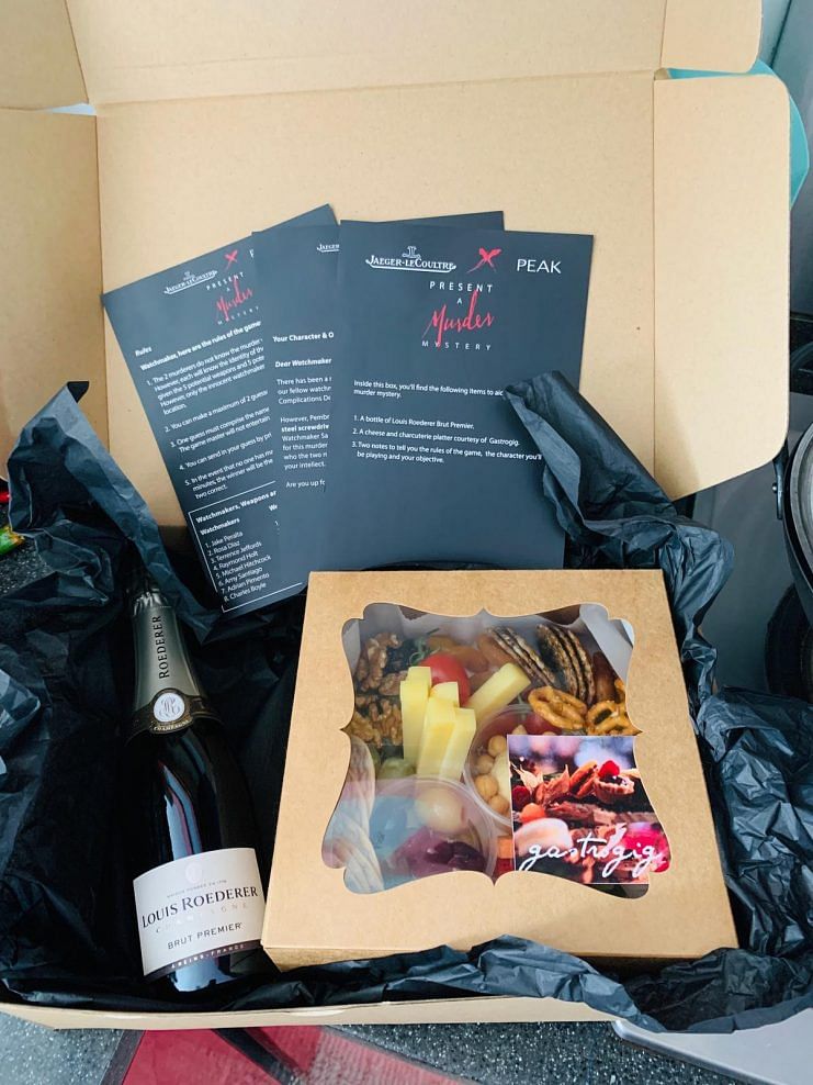 The game package comprising the cheese platter, a bottle of champagne, and game cards that was delivered to all participants.