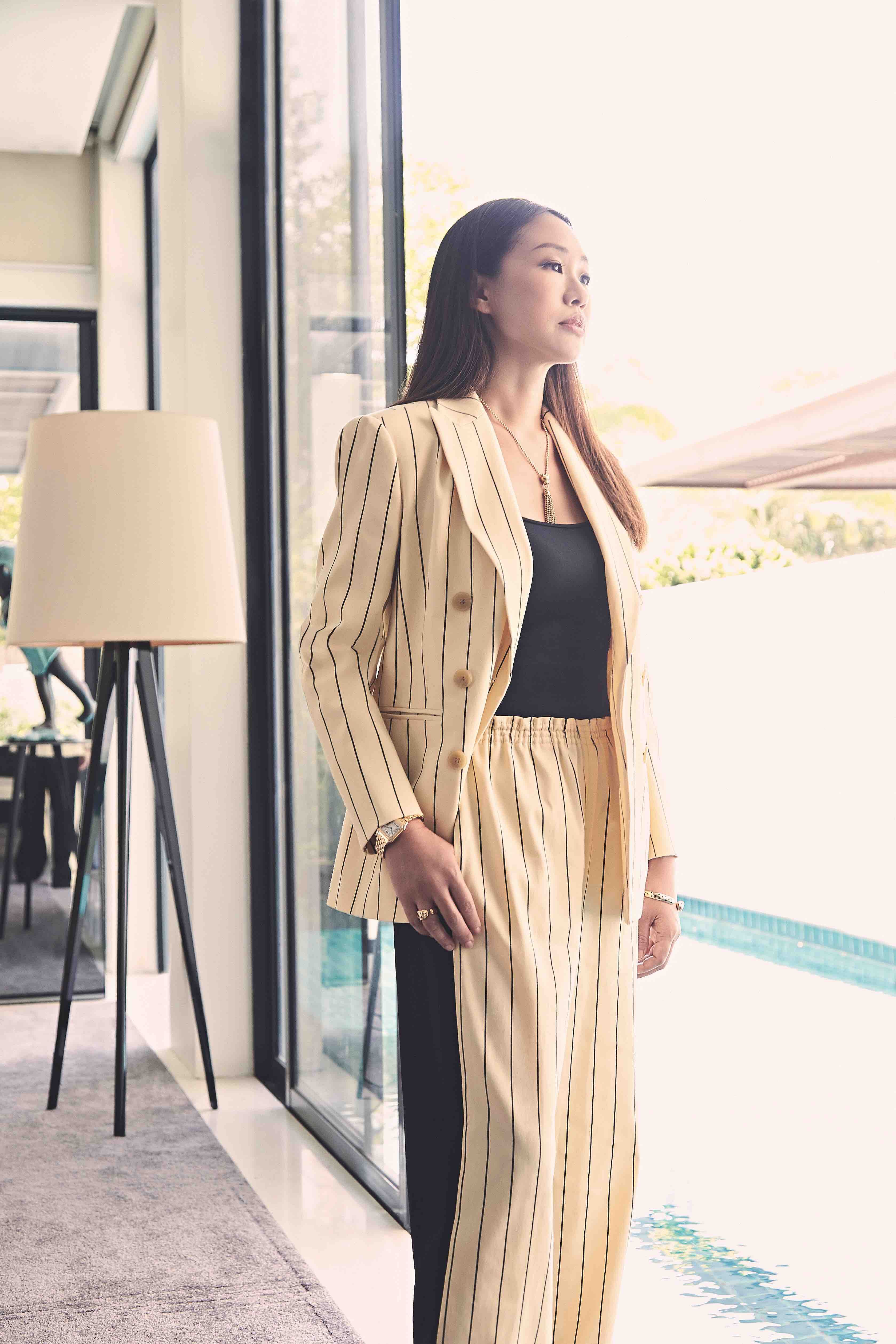 Sharon Sim is wearing a yellow striped cotton mixed pant suit, black leather loafer pumps from Tory Burch. All accessories and watches are from Cartier.