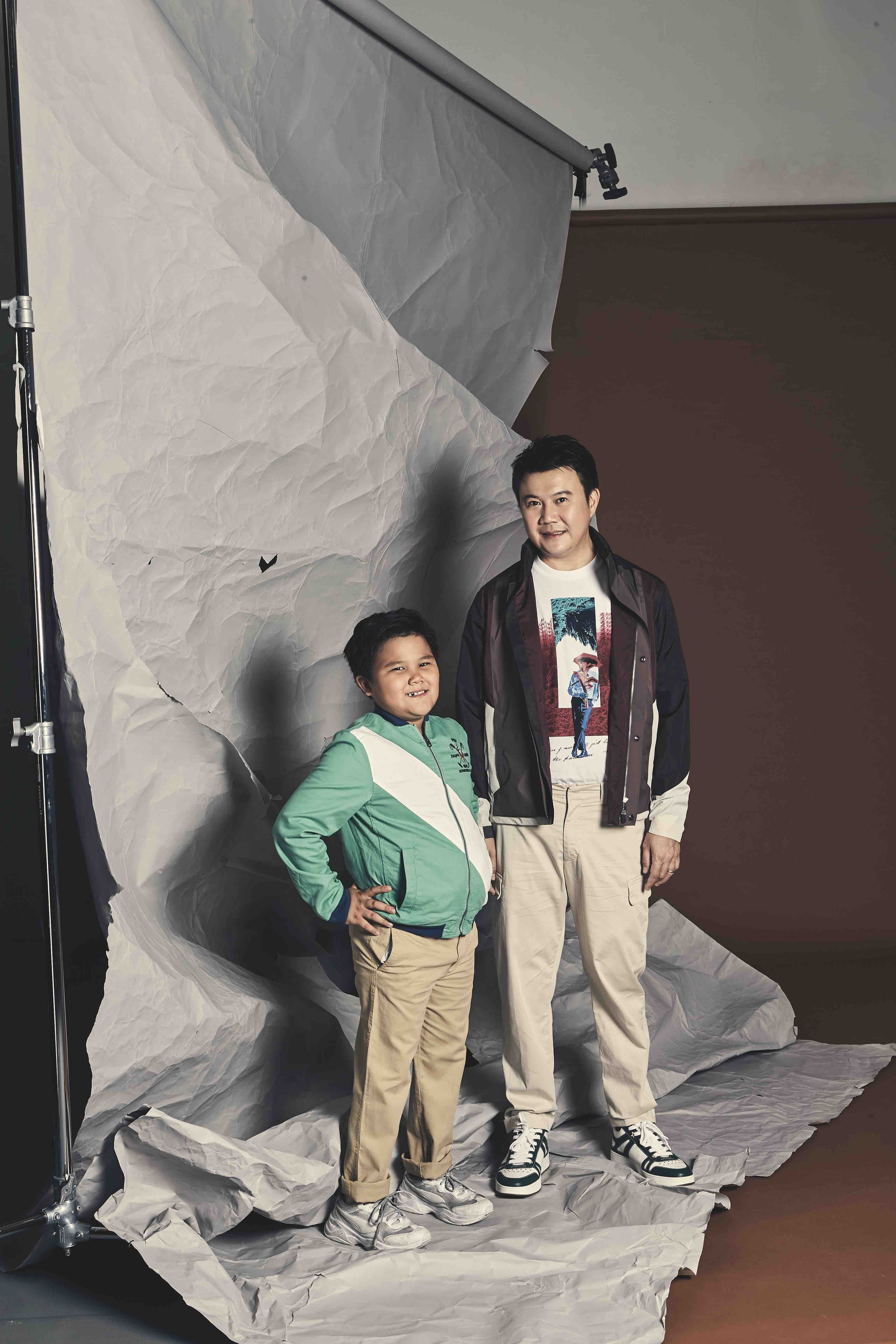 Lester is wearing a cotton printed t-shirt, #UseTheExisting soft shell jacket and  ivory cotton cargo pants from Z Zegna. His white & green leather sneakers are from Jimmy Choo. His son is wearing a green cotton jacket and khaki cotton chino pants from Polo Ralph Lauren.